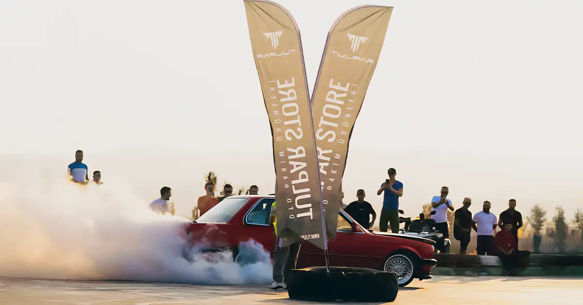 kırmızı renkli bmw e30 aracı tulpar store bayrakları etrafında drift